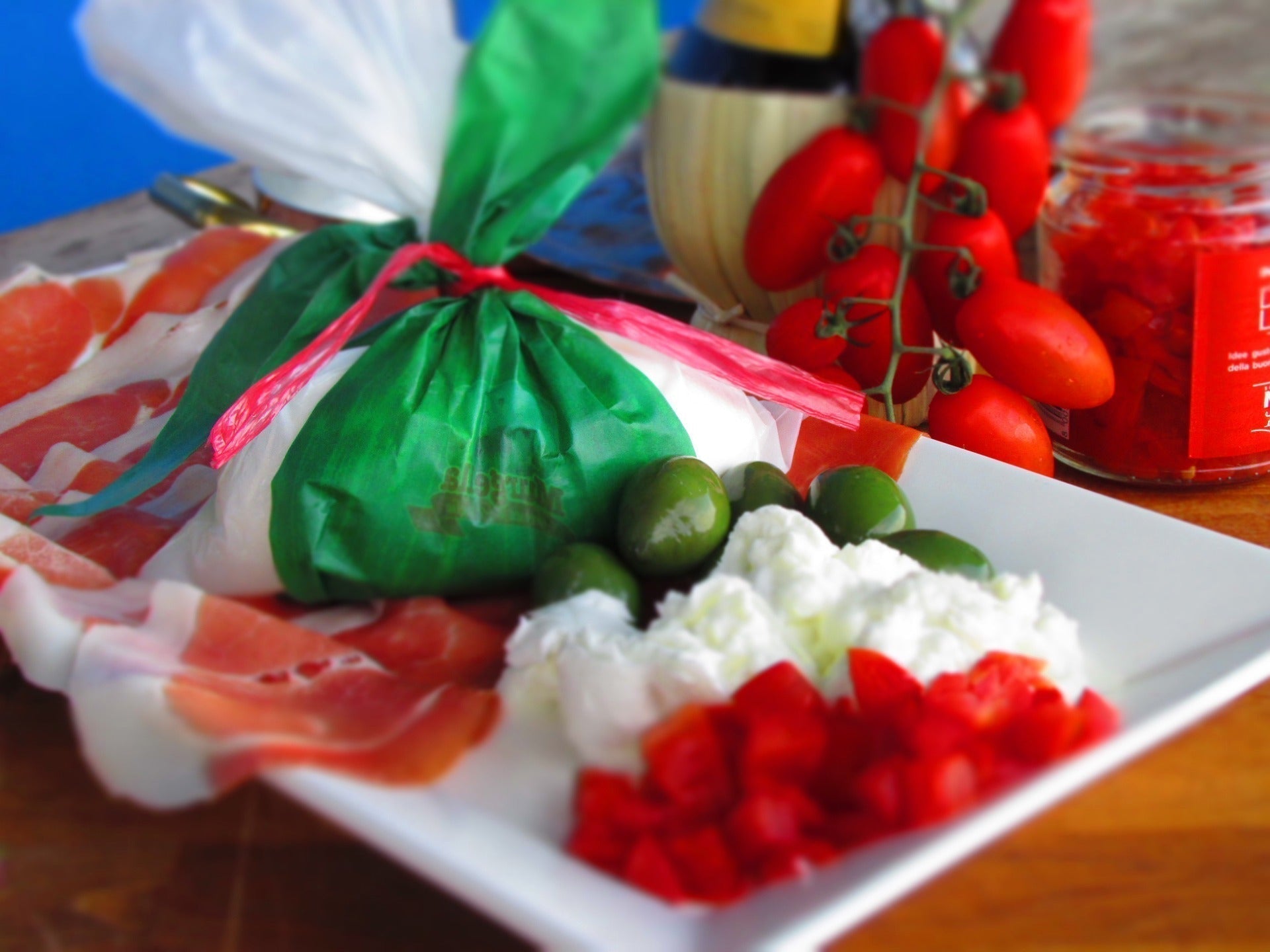 Burrata auf weißem Teller mit Rohschinken und Tomaten